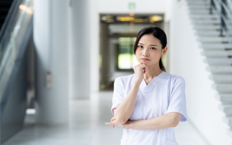 複数の業務を抱えて先輩に仕事の優先順位を確認する女性看護師のイメージ